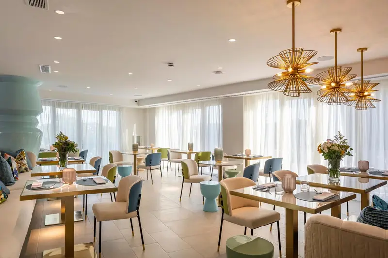 Une salle lumineuse avec des tables dressées et des suspensions décoratives.