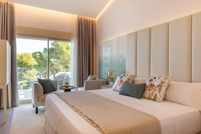 Chambre lumineuse avec un grand lit et un accès à un balcon.