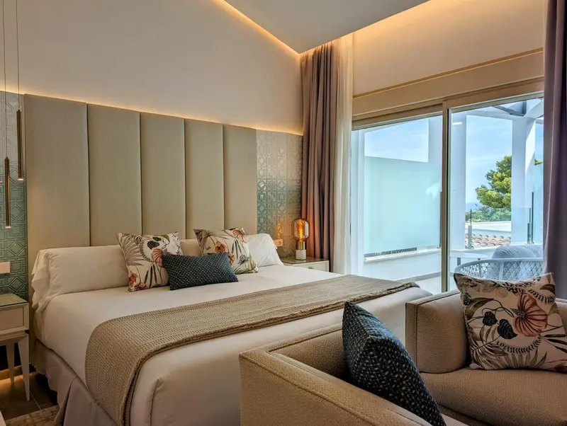Une chambre lumineuse avec un grand lit et un coin salon.