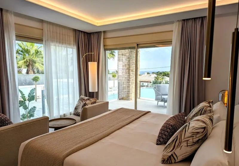 Une chambre lumineuse avec un grand lit et un accès à une terrasse avec vue sur une piscine.