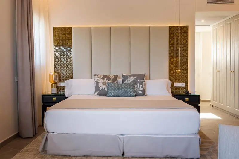 Une chambre avec un grand lit recouvert de draps blancs et de coussins.
