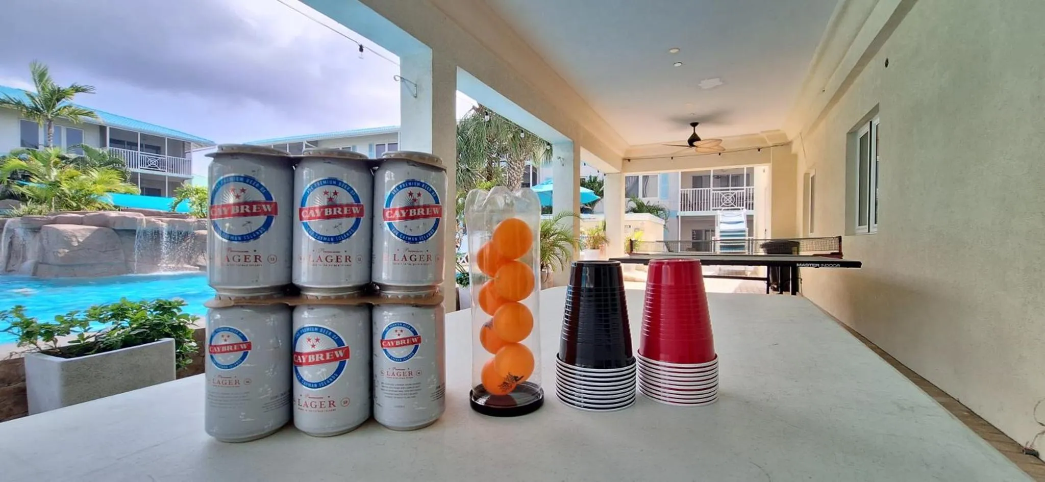 Une table extérieure présente des boissons et des gobelets près d'une piscine.