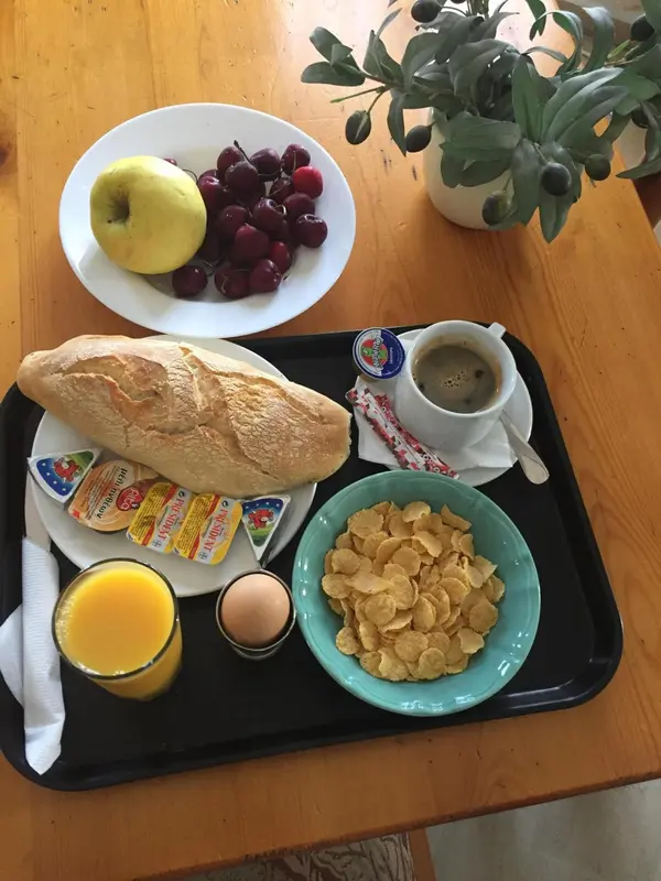 Un petit-déjeuner est présenté sur un plateau noir avec des viennoiseries, des fruits et une boisson chaude.