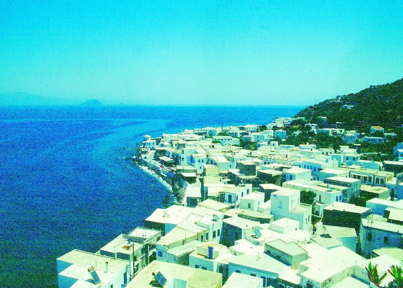 Vue aérienne d'un village blanc surplombant la mer bleue.