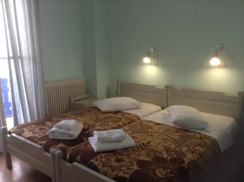 Une chambre avec deux lits simples et des lampes murales.