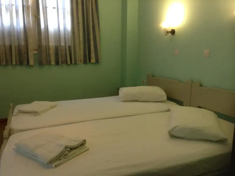 Une chambre lumineuse avec deux lits simples et des murs verts.