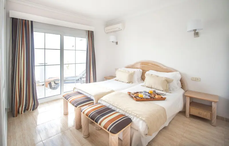 Une chambre lumineuse avec deux lits simples et un petit plateau de petit-déjeuner.