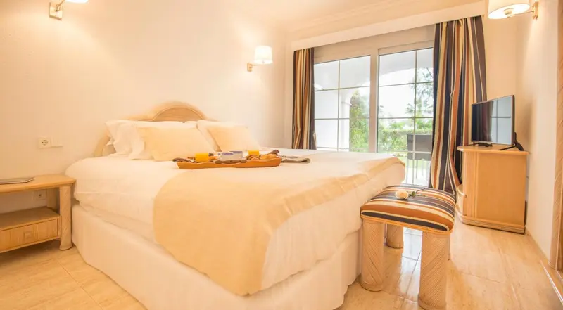 Une chambre lumineuse avec un grand lit et une vue sur l'extérieur.