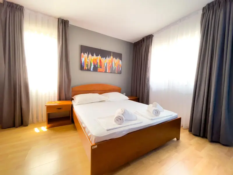 Une chambre lumineuse avec un grand lit et des rideaux gris.