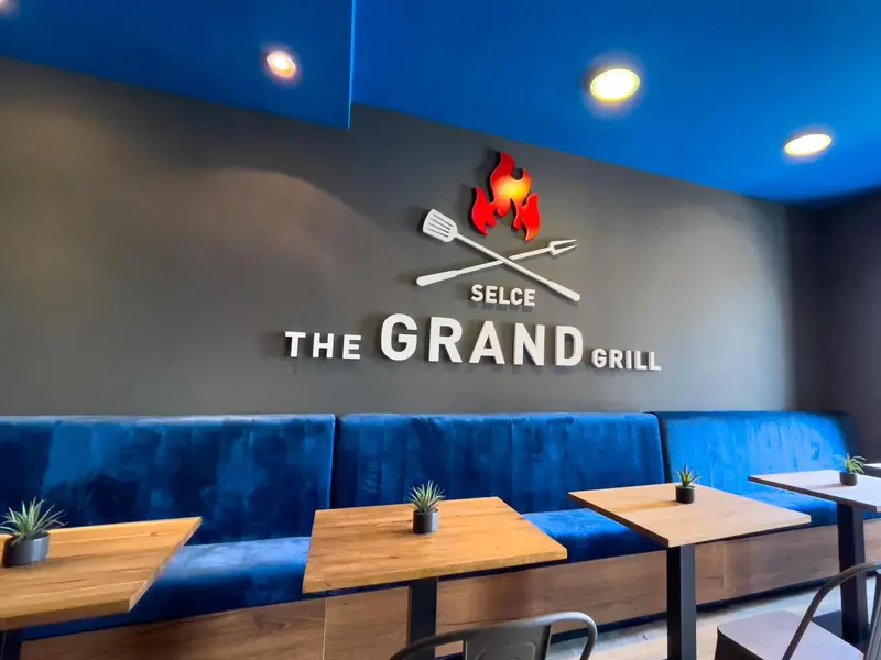 Intérieur d'un restaurant avec des banquettes bleues et des tables en bois.
