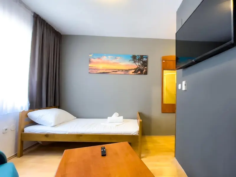 Une chambre lumineuse avec un lit simple et une décoration murale tropicale.
