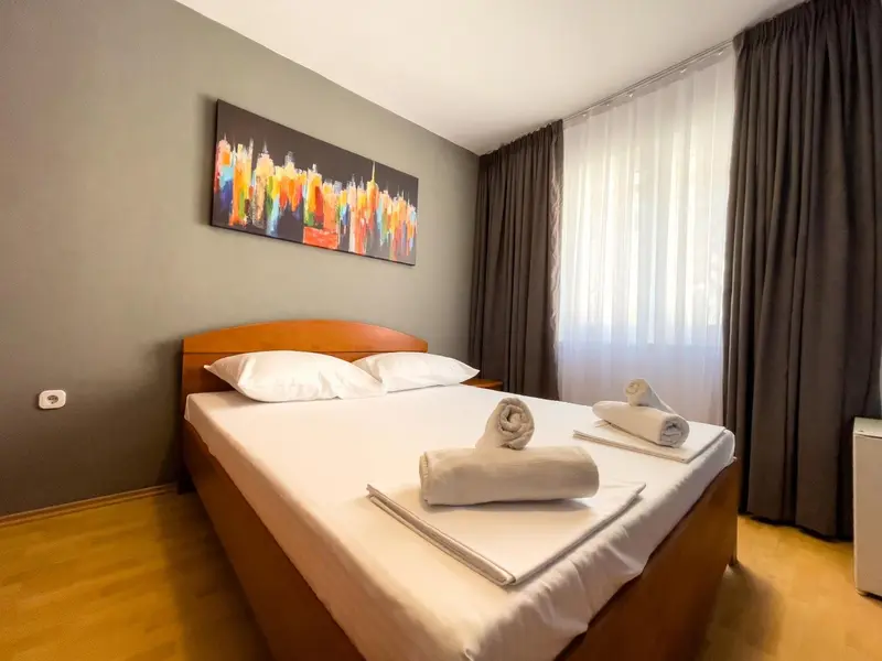 Une chambre lumineuse avec un grand lit recouvert d'une couverture blanche et de serviettes.