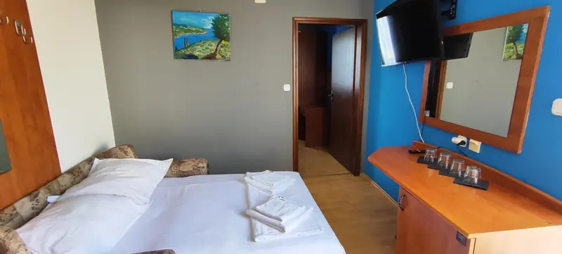 Une chambre lumineuse avec un lit fait et un bureau en bois.