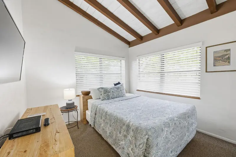 Une chambre lumineuse avec un lit recouvert d'une courtepointe et un bureau en bois.