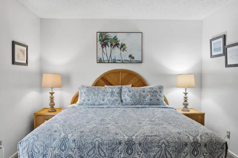 Une chambre lumineuse avec un grand lit recouvert d'une courtepointe décorative.