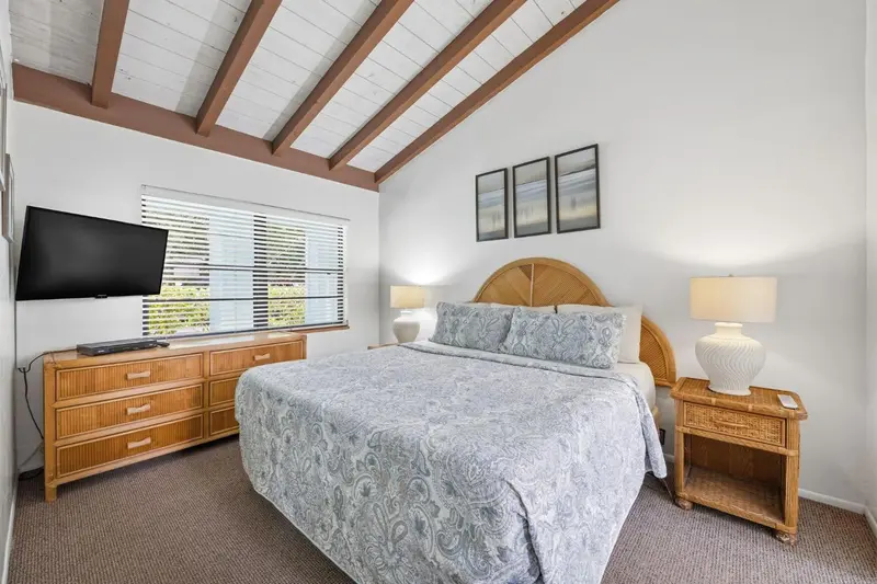 Une chambre lumineuse avec un grand lit et un meuble télévision.