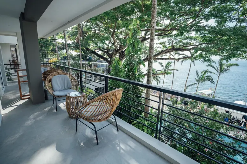 Terrasse aménagée avec des fauteuils en rotin donnant sur la mer.