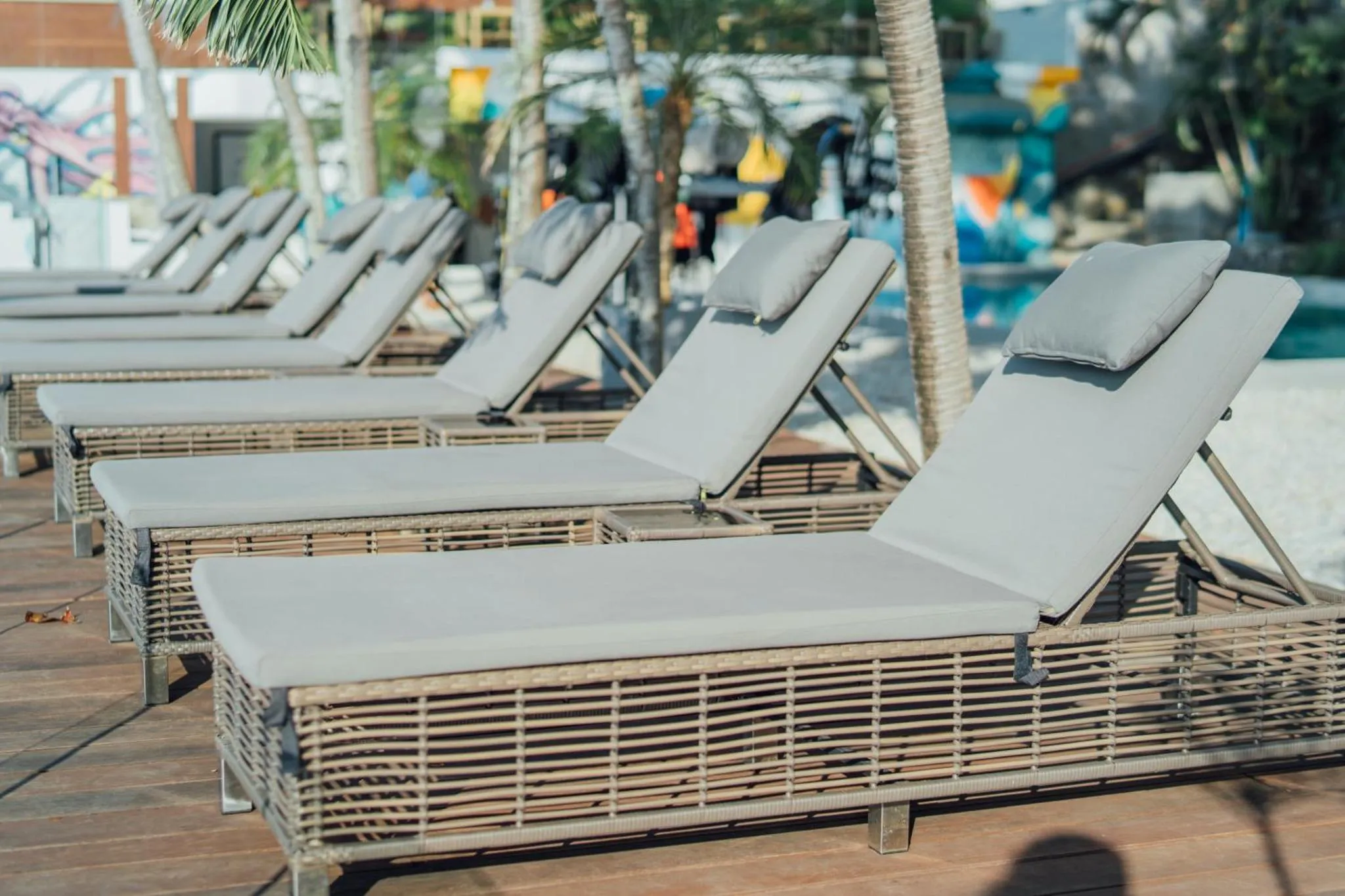 Transats alignés sur une terrasse en bois près d'une piscine.