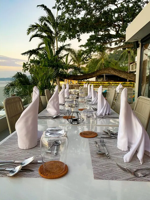 Une table dressée pour un repas en extérieur avec vue sur la mer.