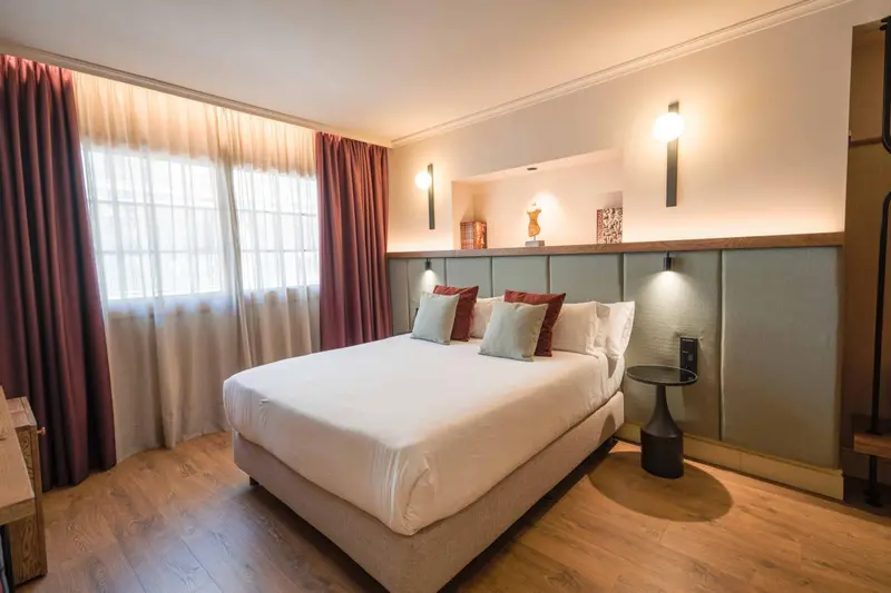 Une chambre lumineuse avec un grand lit recouvert de coussins.