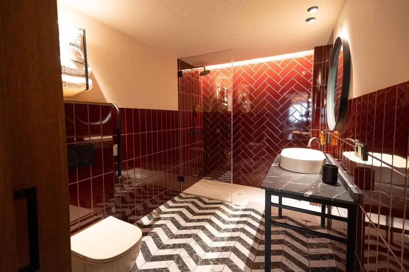 Une salle de bain moderne avec carrelage rouge et sol à motifs.