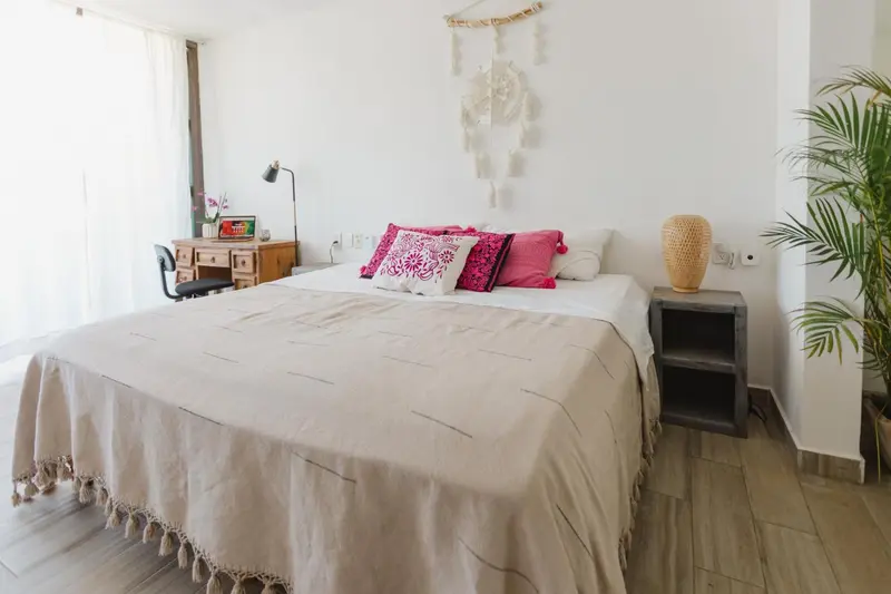 Une chambre lumineuse avec un grand lit recouvert d'une couverture texturée.