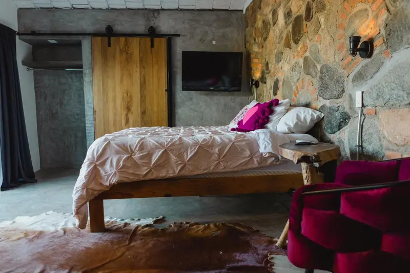 Une chambre à coucher lumineuse avec un lit recouvert d'une courtepointe blanche et des coussins colorés.