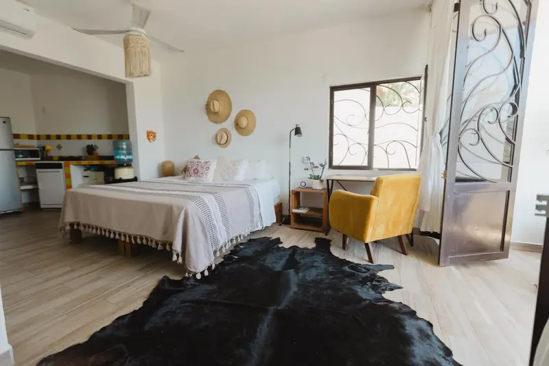 Une chambre lumineuse avec un lit, une kitchenette et un coin salon.
