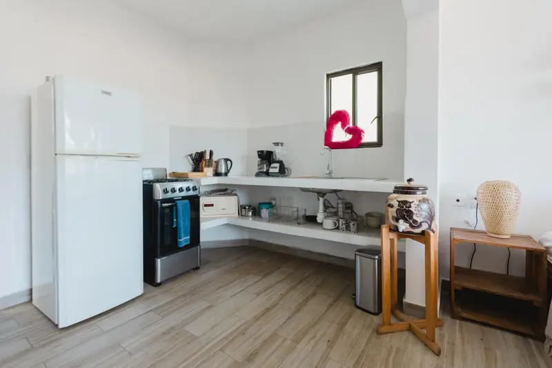 Une cuisine lumineuse avec un plan de travail en arrondi et des appareils électroménagers blancs.