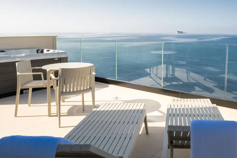Terrasse aménagée avec mobilier de jardin et vue sur la mer.