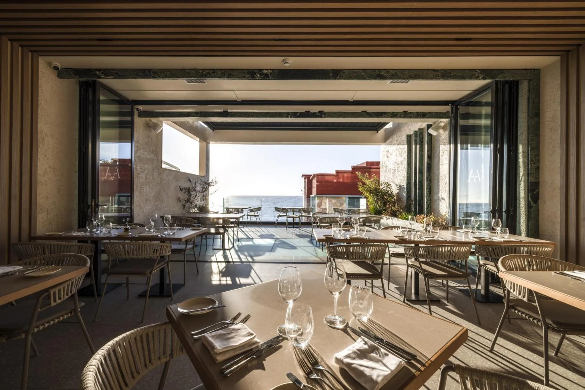 Une salle à manger lumineuse s'ouvre sur une terrasse avec vue sur la mer.