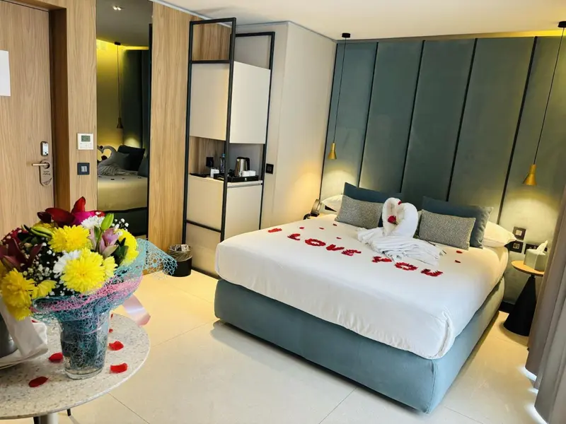 Une chambre d'hôtel décorée avec des fleurs et des pétales de rose sur le lit.