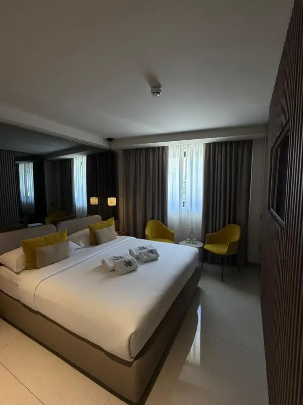 Une chambre lumineuse avec un grand lit et deux fauteuils.