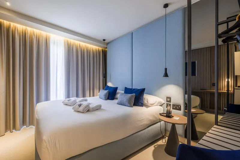 Une chambre lumineuse avec un grand lit et des coussins bleus.
