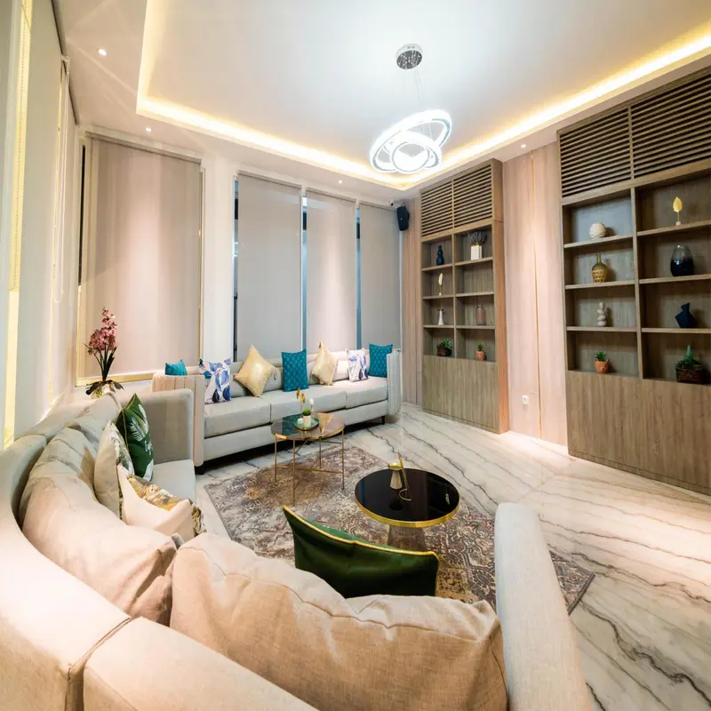 Un salon clair et moderne avec un canapé d'angle et des étagères décoratives.
