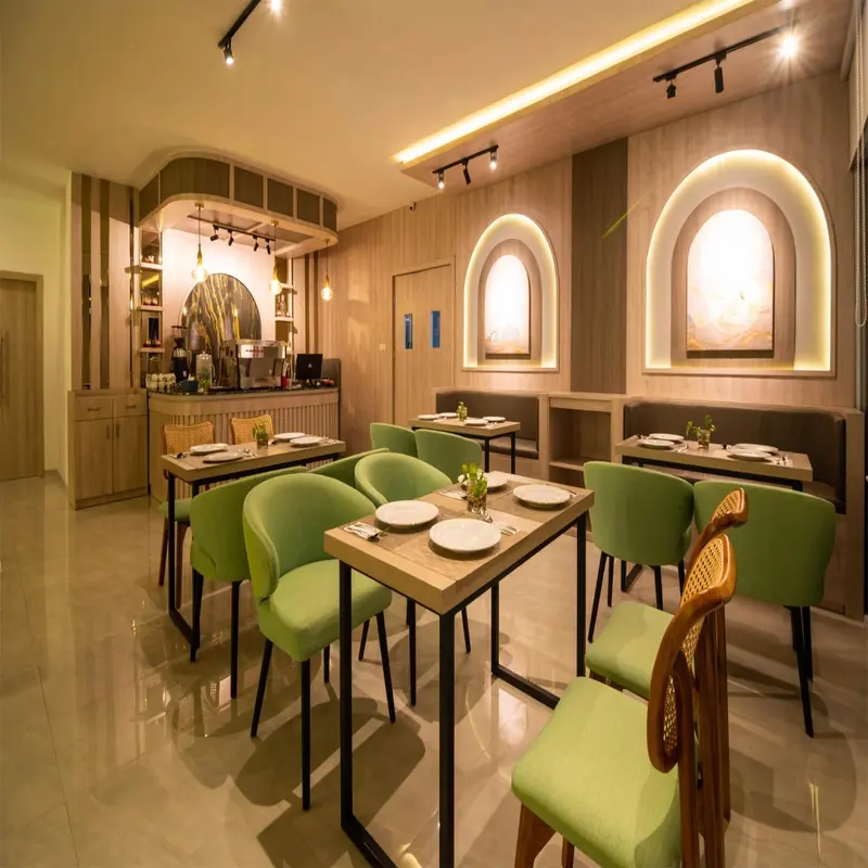 Une salle de restaurant lumineuse avec des tables vertes et des arches décoratives.