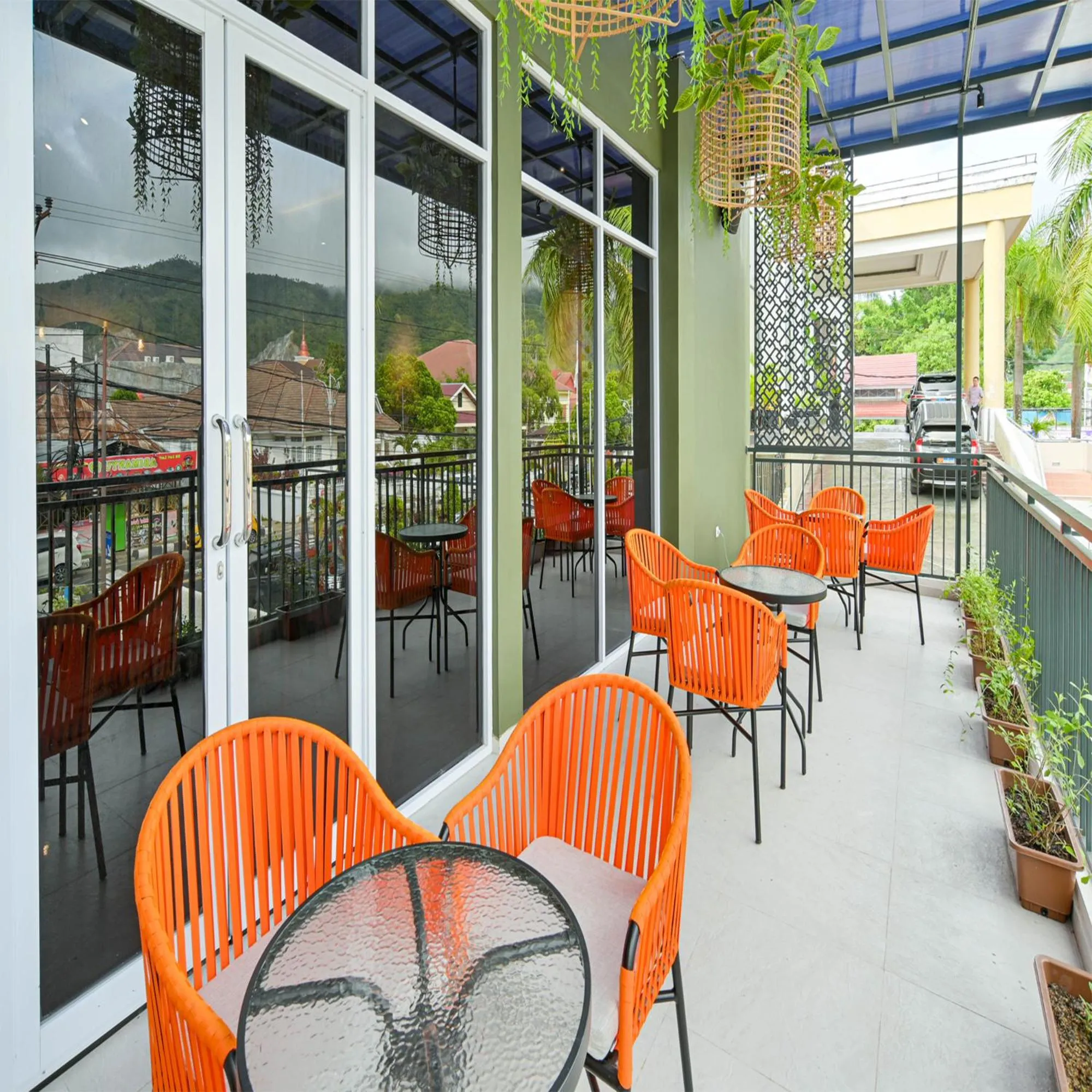 Terrasse ombragée avec tables et chaises orange.