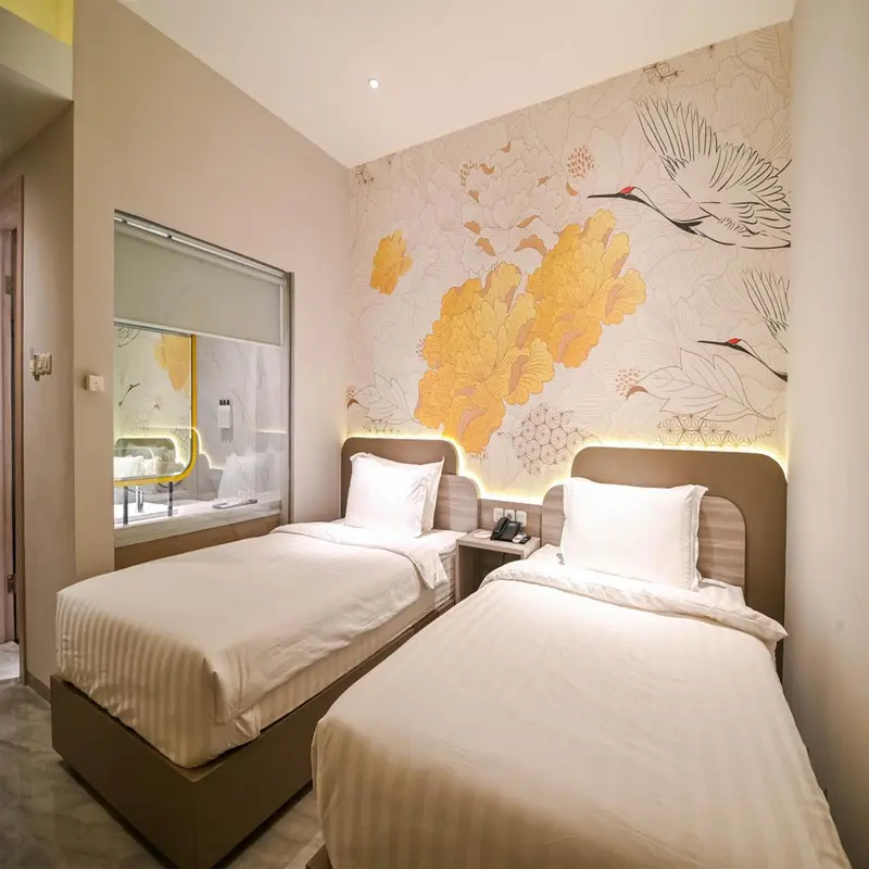 Chambre avec deux lits simples et un mur décoré de motifs floraux.