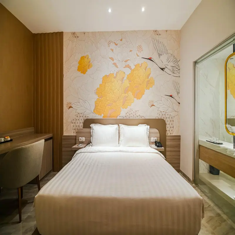 Une chambre lumineuse avec un grand lit et un décor floral sur le mur.