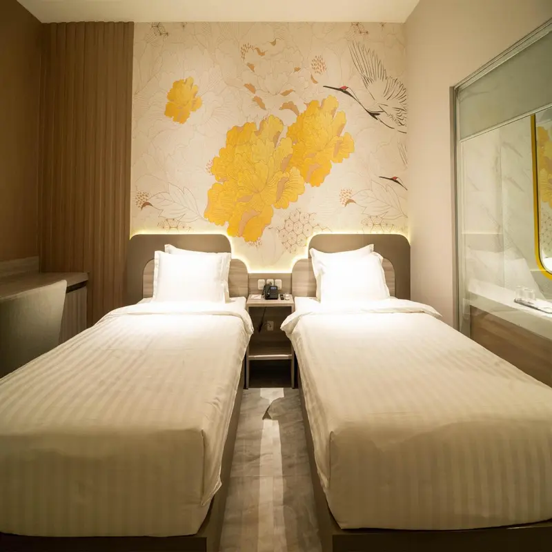 Chambre avec deux lits simples et un mur décoré de motifs floraux.