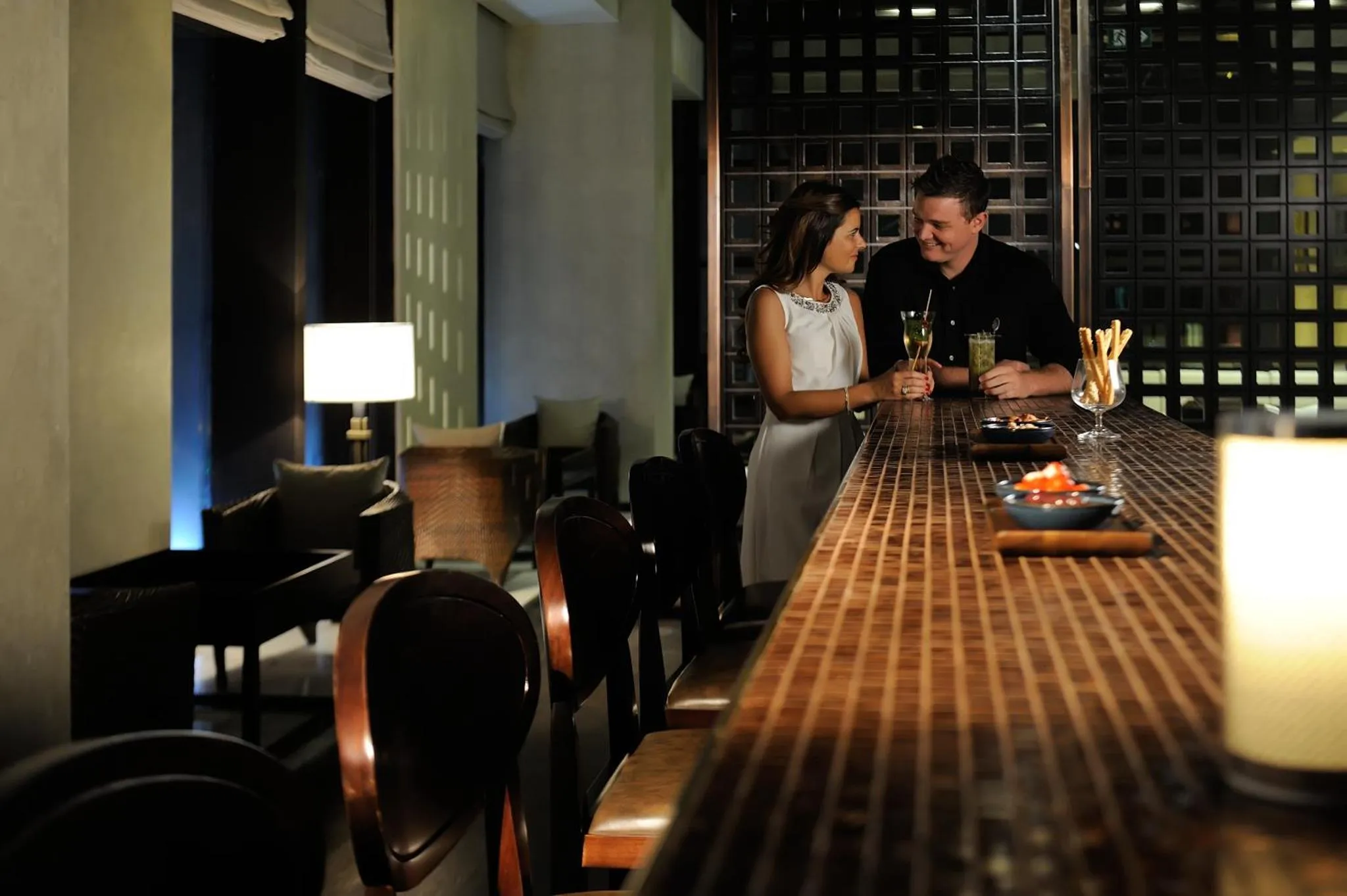 Un couple se tient près d'un comptoir de bar éclairé.
