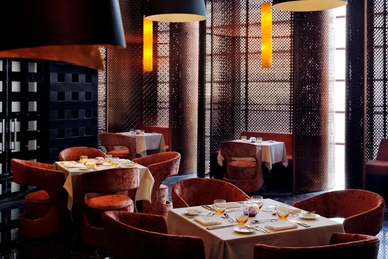 Une salle de restaurant élégante avec des tables dressées et un éclairage tamisé.