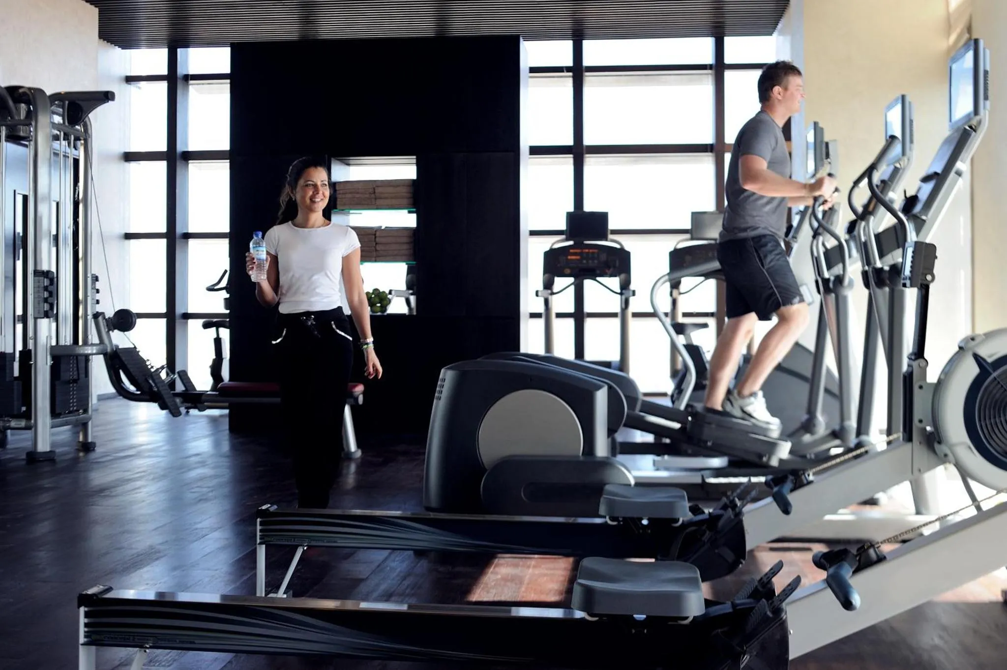 Une salle de sport lumineuse avec des équipements de fitness et des personnes s'entraînant.