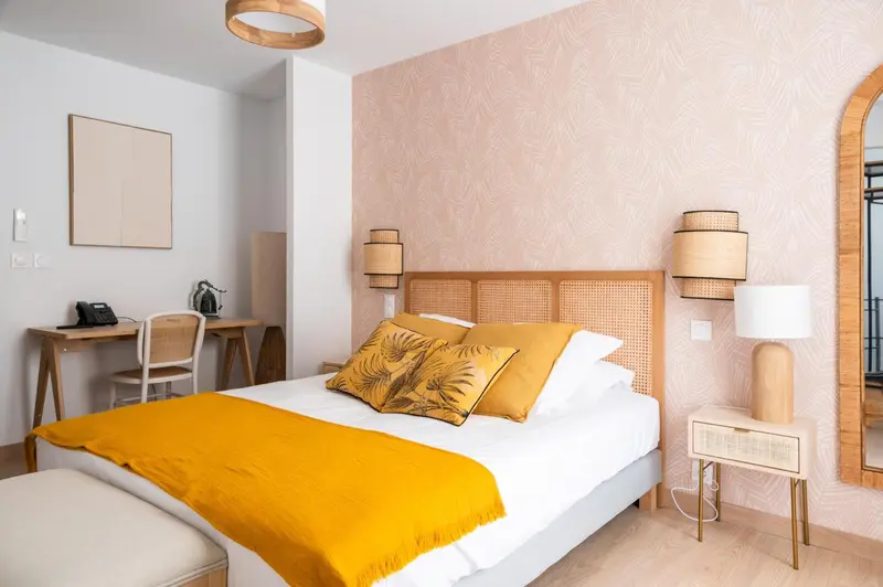 Une chambre lumineuse avec un lit recouvert d'une couverture jaune et un bureau en bois.