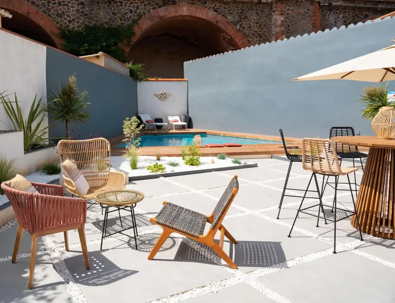 Espace extérieur aménagé avec piscine, mobilier de jardin et bar.