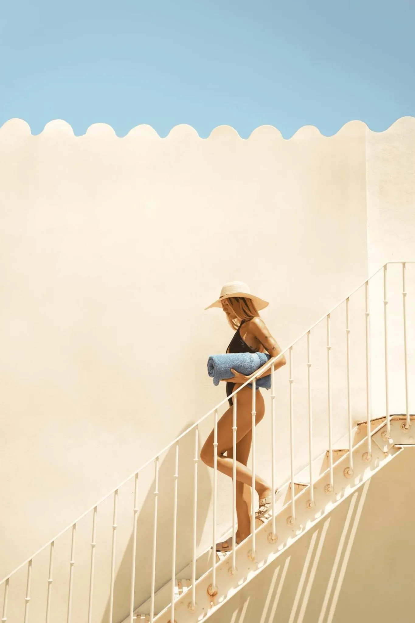Une personne descend un escalier blanc en bord de mer.