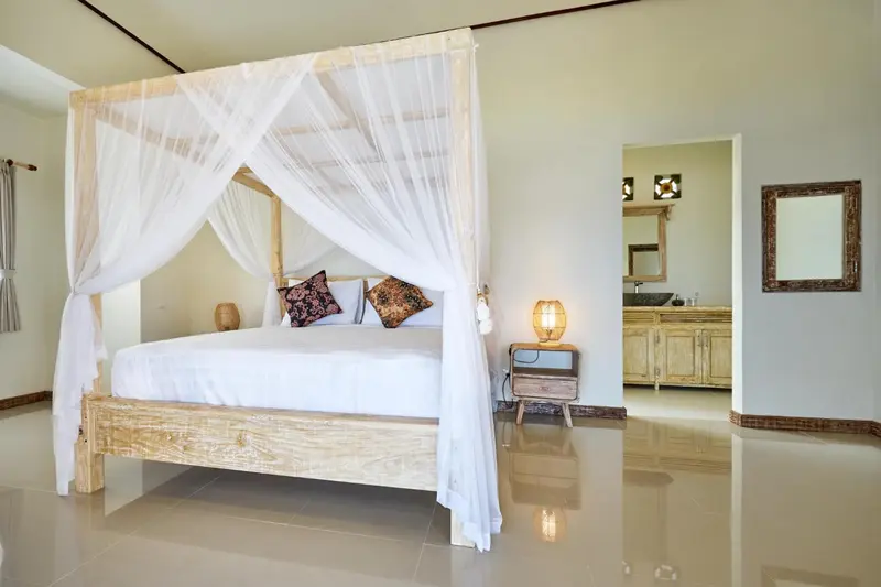 Une chambre lumineuse avec un lit à baldaquin et une décoration sobre.