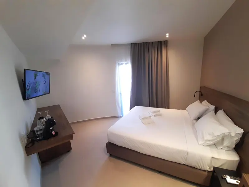 Une chambre lumineuse avec un grand lit et une télévision murale.