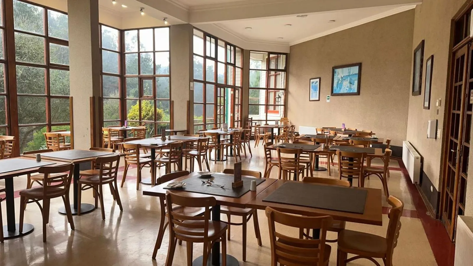 Une salle lumineuse avec des tables et des chaises disposées pour les repas.