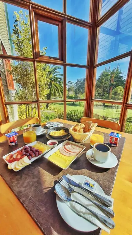 Une table est dressée avec un petit-déjeuner face à une grande baie vitrée.